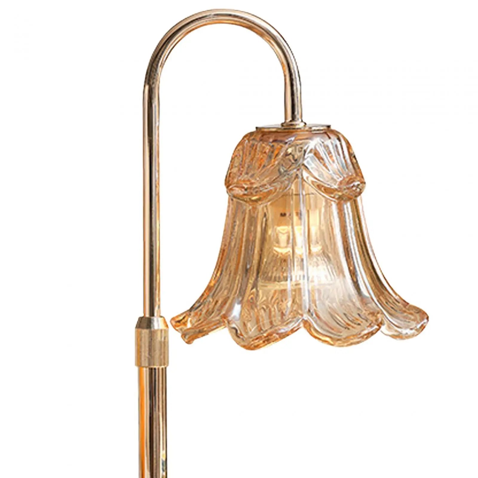 Decorative floor lamp with a glass shade and gold metal arm on a white background