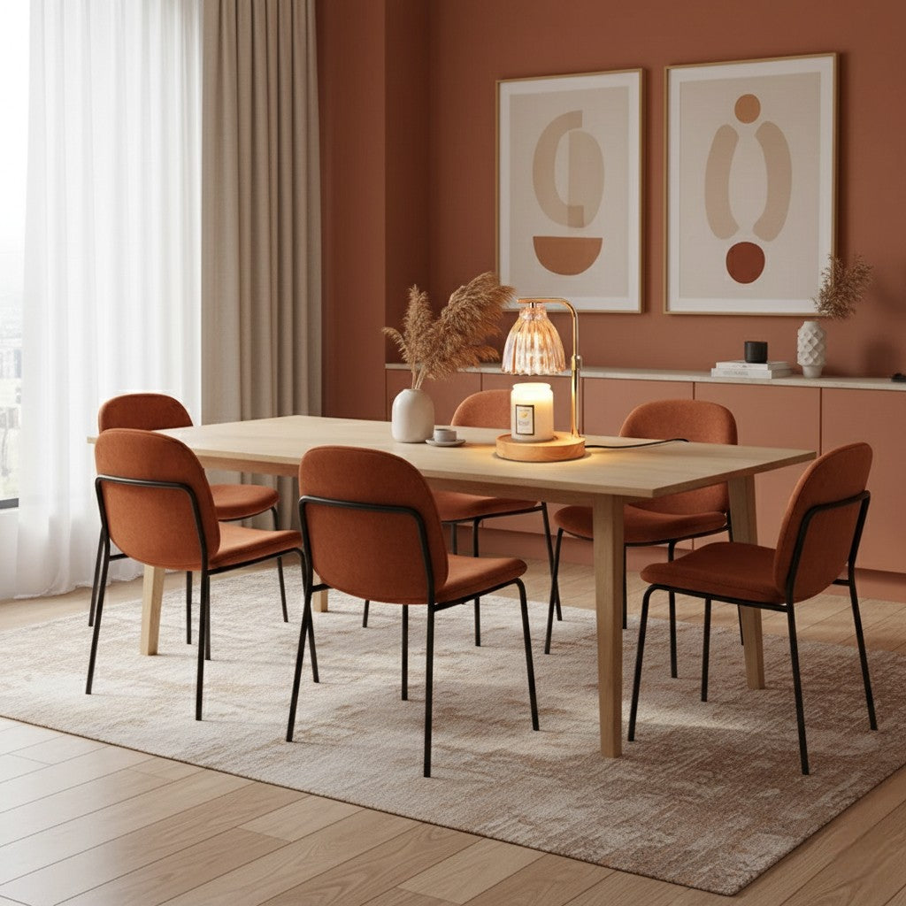 Dining room with a wooden table and orange chairs against a red wall with abstract art.