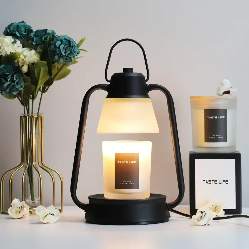 Black lantern with a lit candle labeled 'Taste Life' on a table with flowers and another candle in the background.